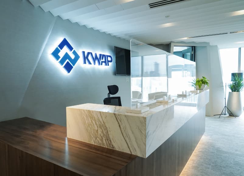 Kaunter penerimaan tetamu KWAP dengan logo KWAP bercahaya di dinding